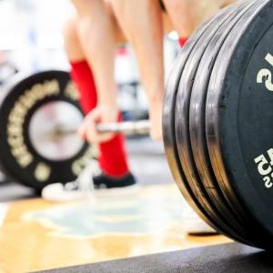 A person picks up weights in a gym.