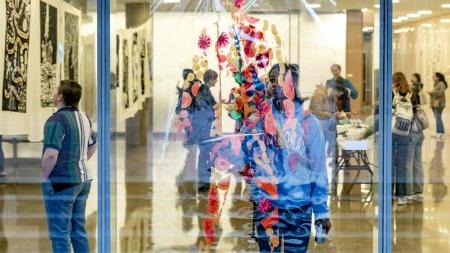 A student looking at a transparent art exhibit.