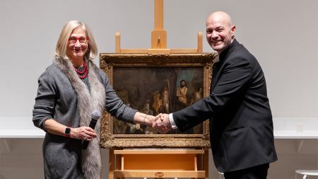 Raphaël Falk and Katie Ziglar shake hands in front of framed artwork; 