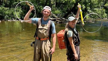 Tayton Alvis and Jenna Jordan holding backpack shockers during fish sampling at the Cullasaja River.