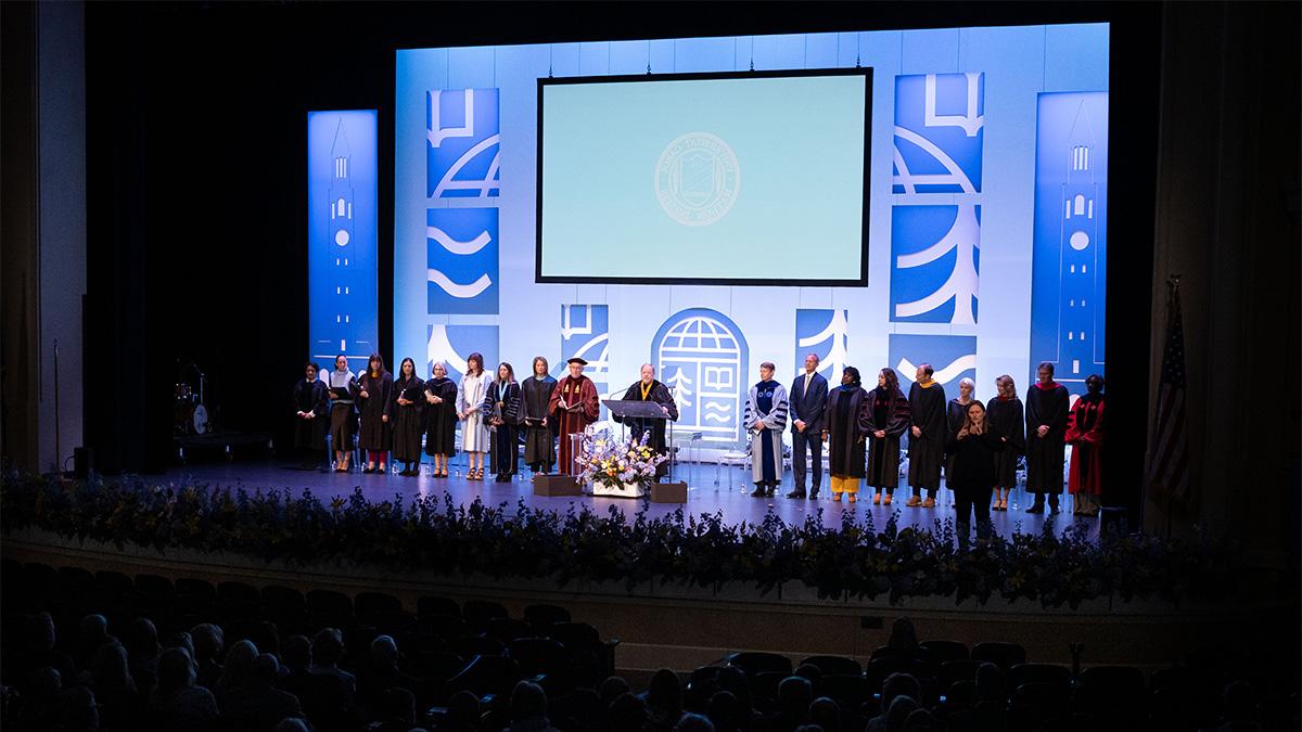 University leaders on stage at Memorial Hall during UNC-Chapel Hill's University Day celebration that included the installation of Lee H. 罗伯茨. 博彩平台大学系统 President Peter Hans is speaking from a podium.